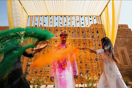 Guests throwing orange colour in front of a terracotta wall