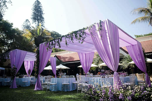 A lilac-draped mandap on a lawn by the trees