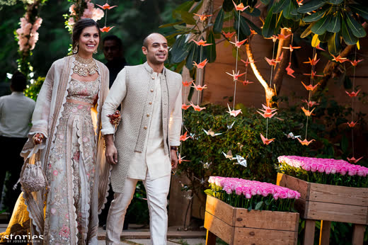 A couple walking out under strings of paper cranes and pink flowers