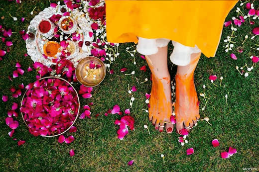 A bride’s hennaed feet on a carpet of rose petals and marigold