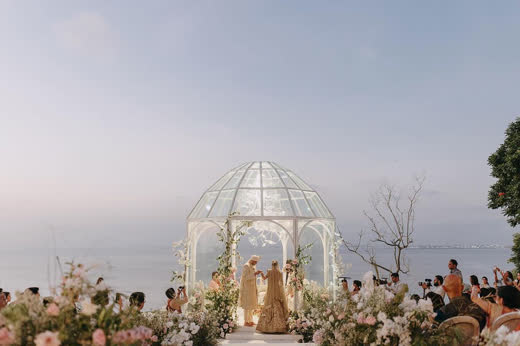 Guests gathered round a white wrought-iron gazebo on a cliff above the sea